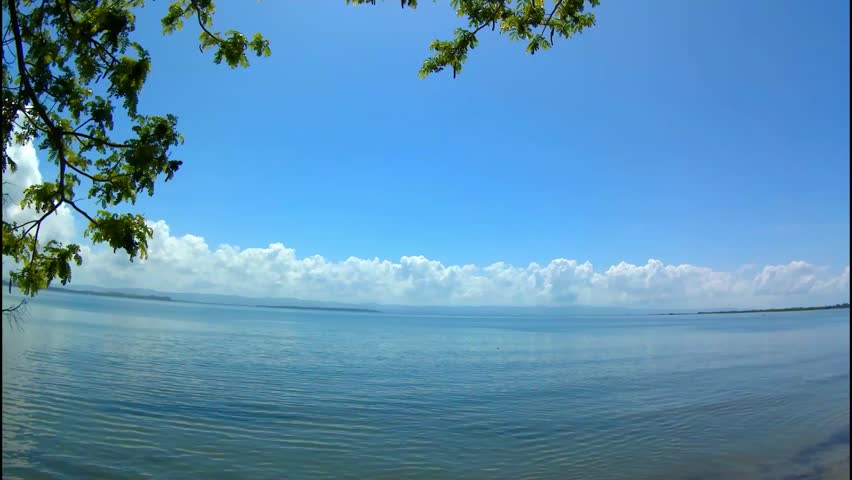 Sea, island, mountains, clouds, fishing boats. Time lapse