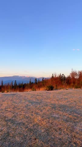 A beautiful sunrise lights up the sky with orange hues. The sun rises above the hills and clouds, creating a colorful morning in the Carpathian mountains.