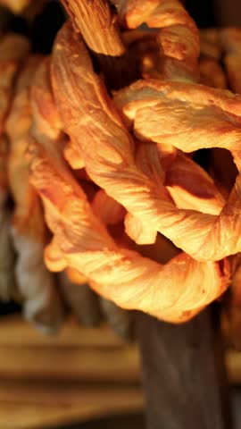 Golden baked pretzel hanging on display. Fresh pastry snack close up in bakery. Tasty knotted dough product for traditional breakfast or food celebration concept.