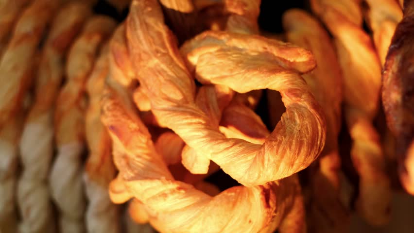 Golden baked pretzel hanging on display. Fresh pastry snack close up in bakery. Tasty knotted dough product for traditional breakfast or food celebration concept.