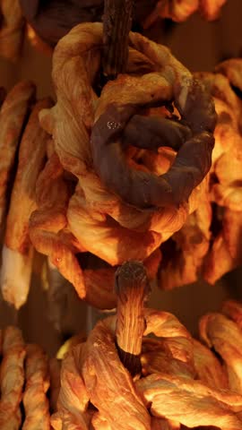 Chocolate dipped pretzel hanging on a shelf in a bakery. Fresh golden brown pastry snack. Sweet dessert food display for cafe breakfast or gourmet coffee shop.