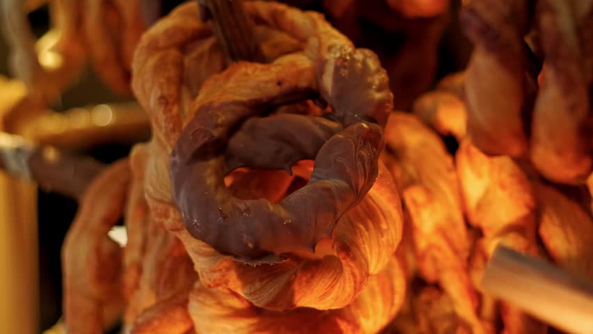 Chocolate dipped pretzel hanging on a shelf in a bakery. Fresh golden brown pastry snack. Sweet dessert food display for cafe breakfast or gourmet coffee shop.