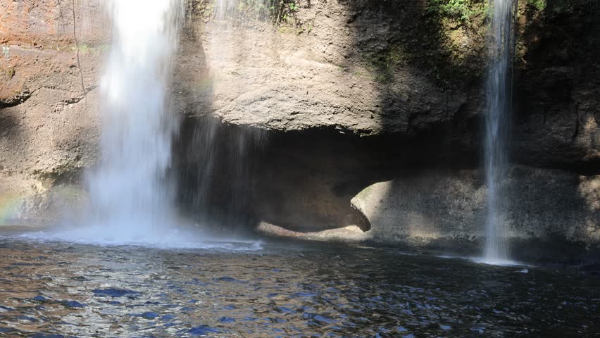 Powerful waterfall flow, splashing water surface, limestone cave background.