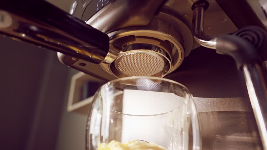 Slow Motion Close Up Of Espresso Machine Showing Incorrect Bottomless Portafilter Extraction With Coffee Spraying And Dripping Uncontrolled Into Cup Creating Messy Brewing Process.