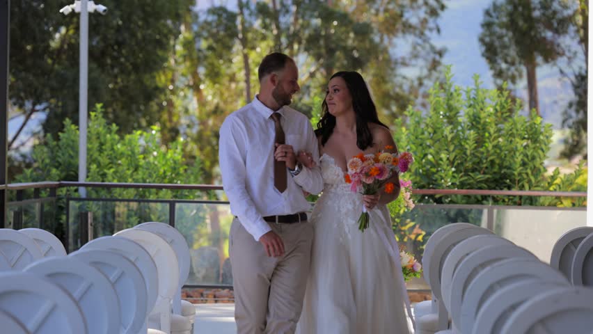 Young bride and groom walking toward camera pause for a quick kiss