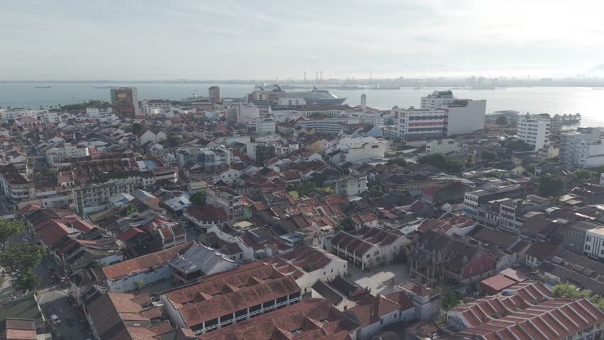 Historic urban preservation and tourism concept: Aerial view of the George Town UNESCO World Heritage Zone in Penang, Malaysia, showcasing traditional red-tile rooftops and heritage shophouses during a bright, quiet morning.