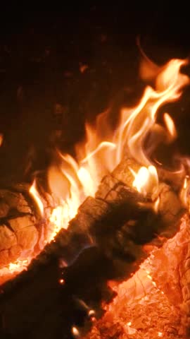 A home fireplace with a bright orange flame and logs burns and warms the room. Comfort and warmth in the cold winter atmosphere.