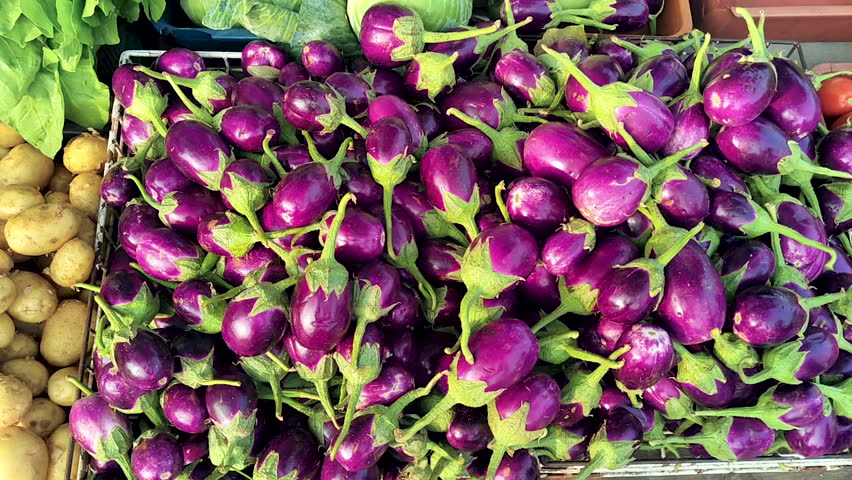 Close-up of fresh eggplants and potatoes at street market. Ideal for food retail, grocery shopping, organic produce, healthy eating and farm-to-table concepts.