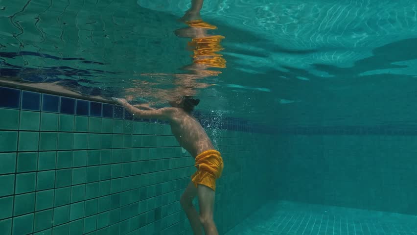 Cute Kid Dives in the blue water Pool.