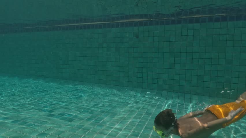 Cute Kid Dives in the blue water Pool.