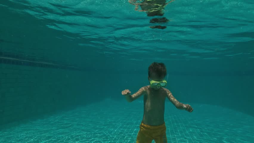 Cute Kid Dives in the blue water Pool.