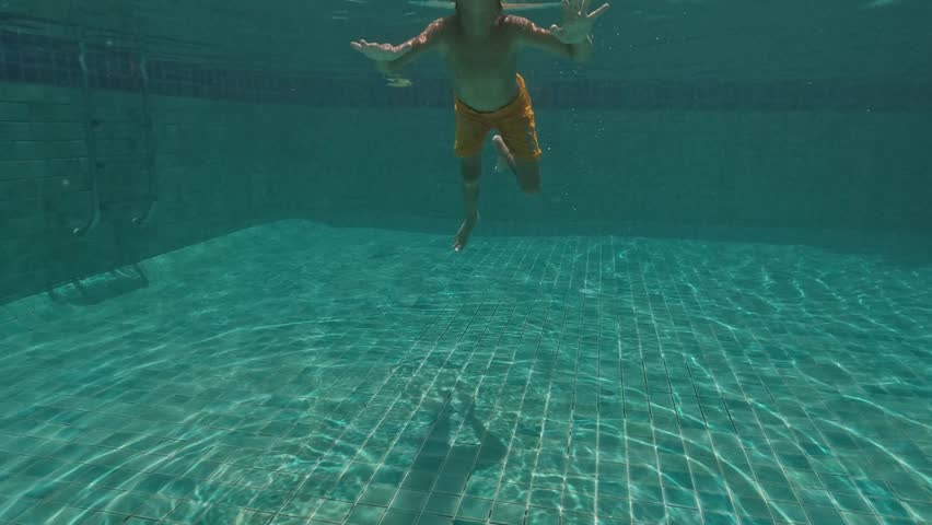 Cute Kid Dives in the blue water Pool.