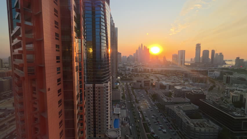 Dubai skyline at sunset with high rise towers and city streets below, warm golden light over modern buildings and distant waterfront cityscape