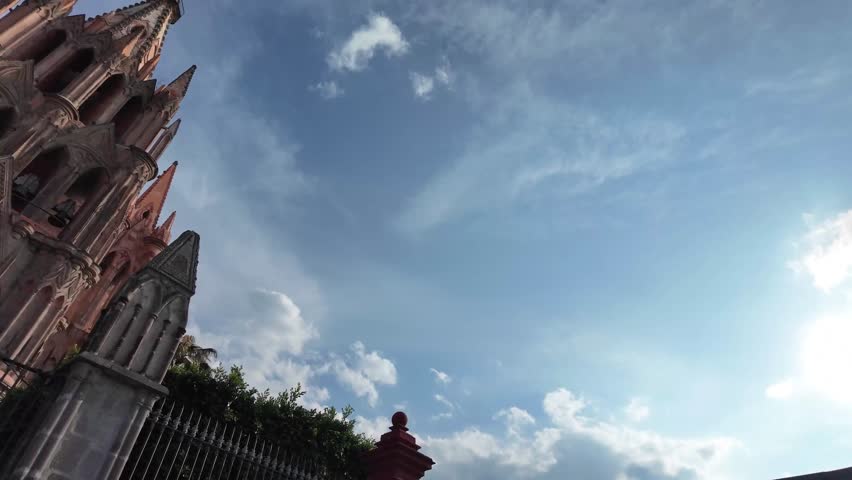 Wide shot exploring a majestic red stone church under a clear blue sky.