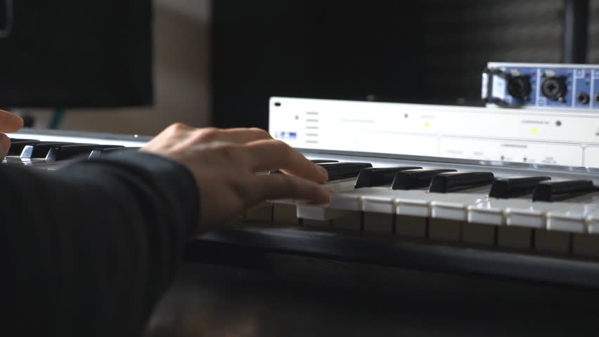 Hands of male musician playing at synthesizer. Mens arms plays solo of music or new melody. Close up fingers of pianist at the piano keys. Slow motion Rear back view Isolated shot