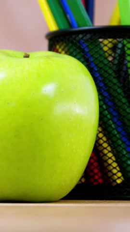 Pen holder with color pencil and apple on wooden table 4k