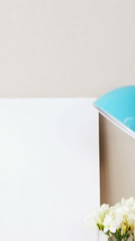 Stack of books, blank board, flower vase, cup of tea and table lamp at home