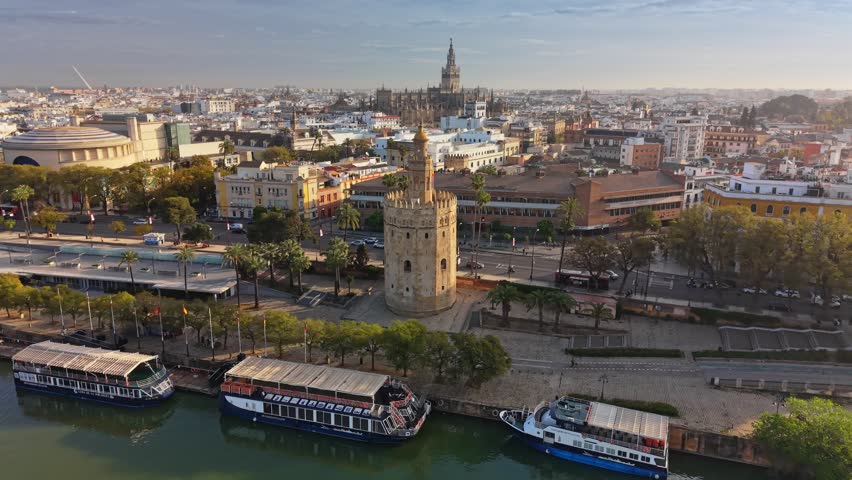 Beautiful aerial reveal of the Torre del Oro and Seville Cathedral at sunrise, Seville, Spain. historic center of Seville featuring the grand cathedral and Giralda tower