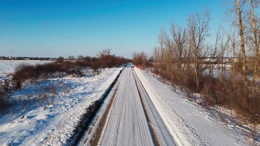 Snowy train tracks leading through a winter landscape with trees and bushes