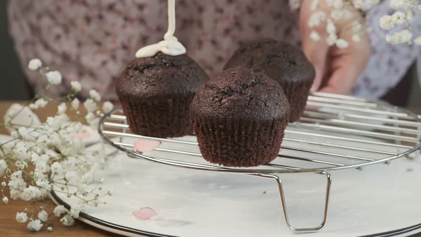 Decorating chocolate cupcakes with icing and edible toppings on a wooden table. Easter treats. Happy Easter.