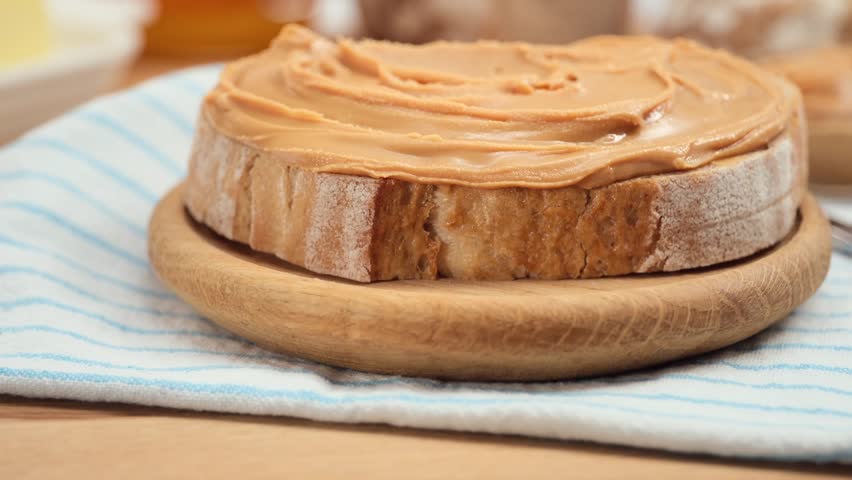 Peanut butter spread on fresh bread slice, homemade breakfast preparation, copy space
