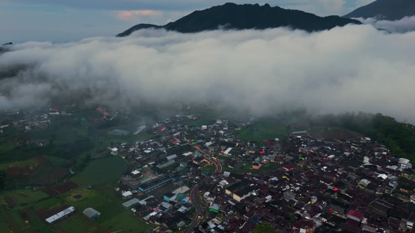 Aerial view of a village nestled among mist covered mountains