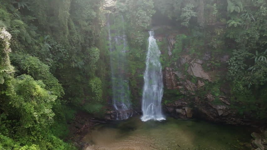 Thác Tiên waterfall medium approach shot showing water spray at the base and surrounding moss-covered rocks, Hà Giang, Vietnam.