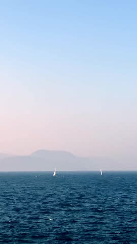 Yachts sailing on calm blue ocean waters under clear sunny skies