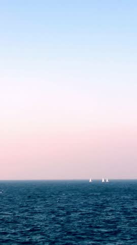 Yachts sailing on calm blue ocean waters under clear sunny skies