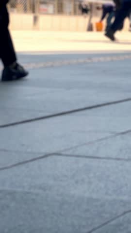 Blurred people walking in modern urban plaza with buildings background