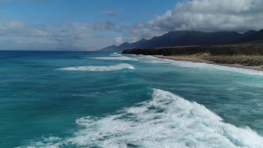 Aerial view of ocean waves crashing on a sandy beach
