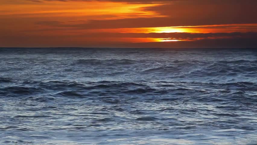 Beautiful orange sunset over the blue ocean waves
