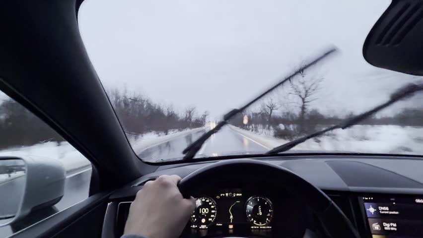 POV Driving a Car on a Wet Winter Road with Snow and Active Windshield Wipers