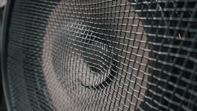 A powerful audio speaker cone pulses and vibrates rapidly behind a dark wire mesh protective cover. Sharp industrial details highlight the rhythmic movement of the diaphragm from heavy bass. - Powered by Shutterstock - Get 15% off with code: PIKWIZARD15