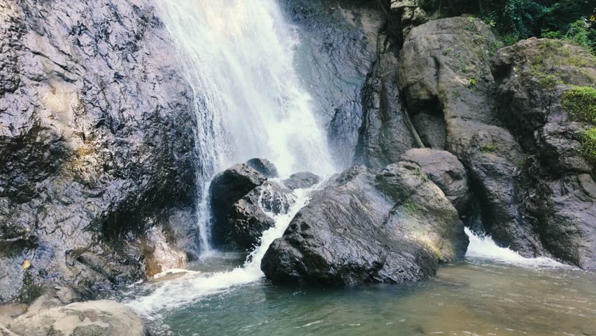 Majestic Waterfall Cascading Over Rocky Cliff Surrounded By Lush Green Forest