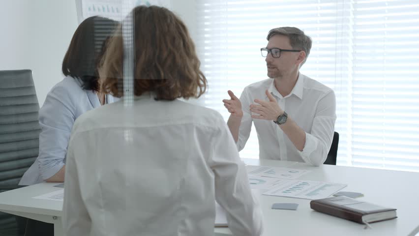 Business professionals collaborating and analyzing data during a team meeting in a modern office, developing new marketing strategies and discussing financial reports