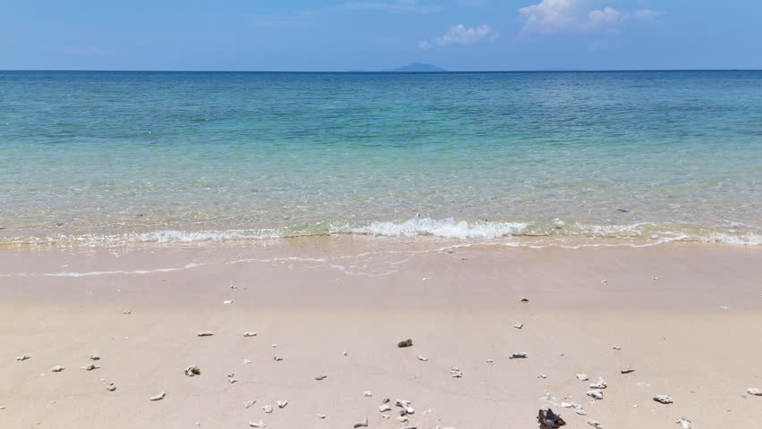 Serene Beach Scene with Clear Blue Water, Sandy Shores, and Distant Island Under Bright Sky with Clouds and Horizon