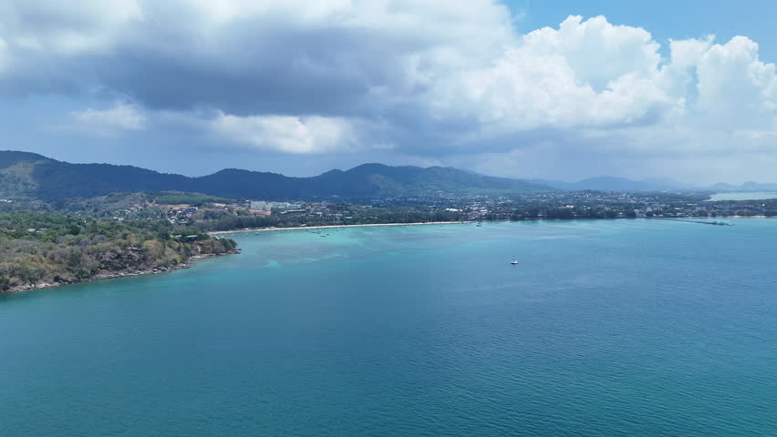 Aerial View of Serene Coastal Landscape with Turquoise Waters and Lush Hills Under Partly Cloudy Sky Evoking Peace and Natural Tranquility