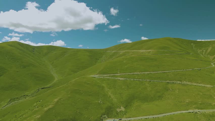Green rolling hills under a blue sky with white clouds