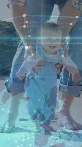 Vertical video: Parent putting baby feet on sand, steadying, tech overlay mapping steps for balance. Infant, caregiver, beach, shoreline, candid, documentary, vertical video