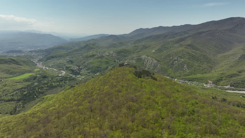 Aerial shot of the Mamkoda Monastery, located near Tbilisi. The image captures the historic stone architecture of the church and its surrounding monastic buildings, set against a backdrop of dense spring forests and rolling mountains.