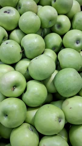 Abundant display of ripe green apples at a local farmers market. Fresh organic fruit harvest. Food background. Healthy eating, vegetarian diet, and juice industry. Natural and crunchy