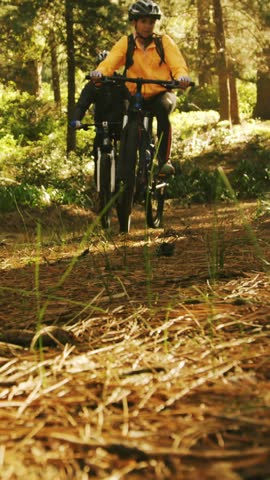 Mountain biking couple riding in the forest on a sunny day 4k