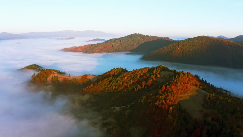 Sunrise light among clouds above mountainous canyon in mist