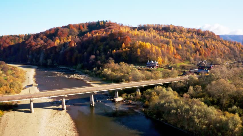 Road bridge over narrow river leading to terracotta forest