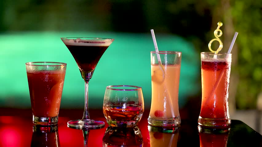 Hand picks up martini glass, other hand reaches for whiskey.