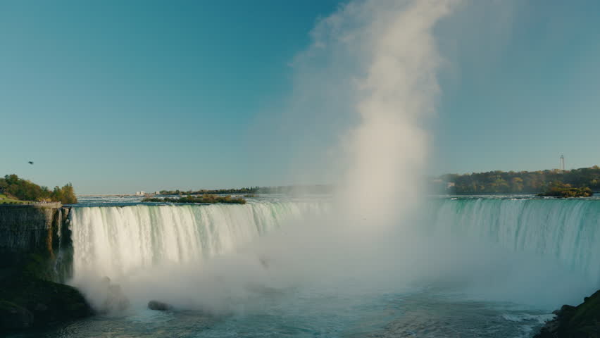 Horseshoe Falls at Niagara Falls with massive water cascade and rising mist cloud on border of Canada and USA.