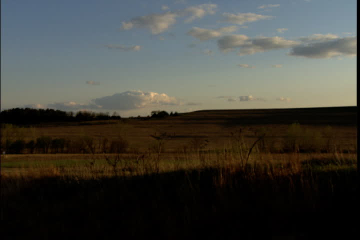 Pan over flat midwest plains to silhouette of a child