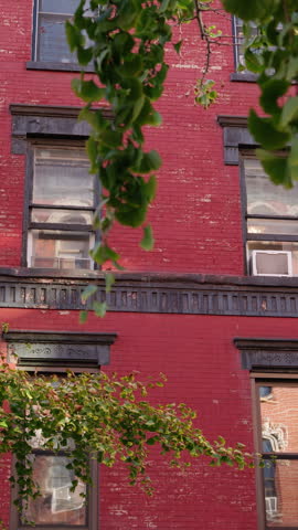 Historic red brick apartment facade with trees in New York City.