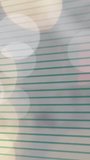 Vertical video: Ruled page showing camera shift causing bokeh drift, pink flash, settling for focus. Notebook, lines, bokeh, closeup, reflections, texture, vertical video - Powered by Shutterstock - Get 15% off with code: PIKWIZARD15